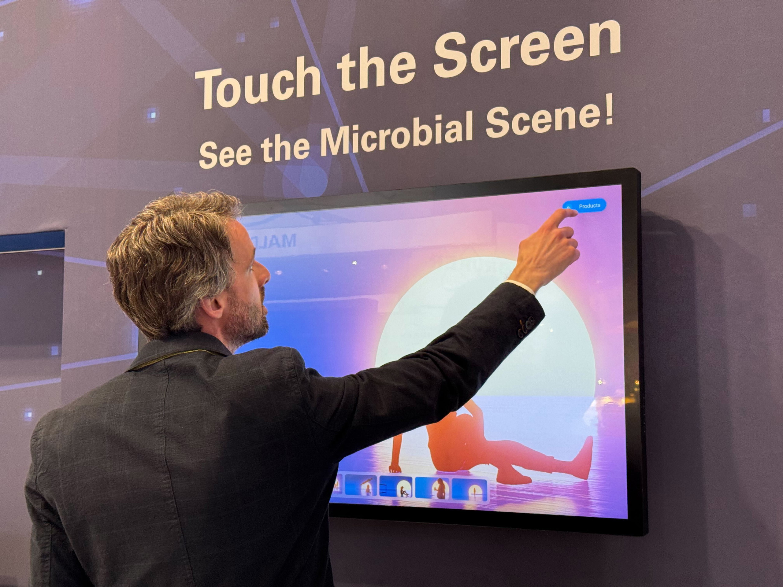Rense in front of ELLA Bruker microbial marathon at conference booth