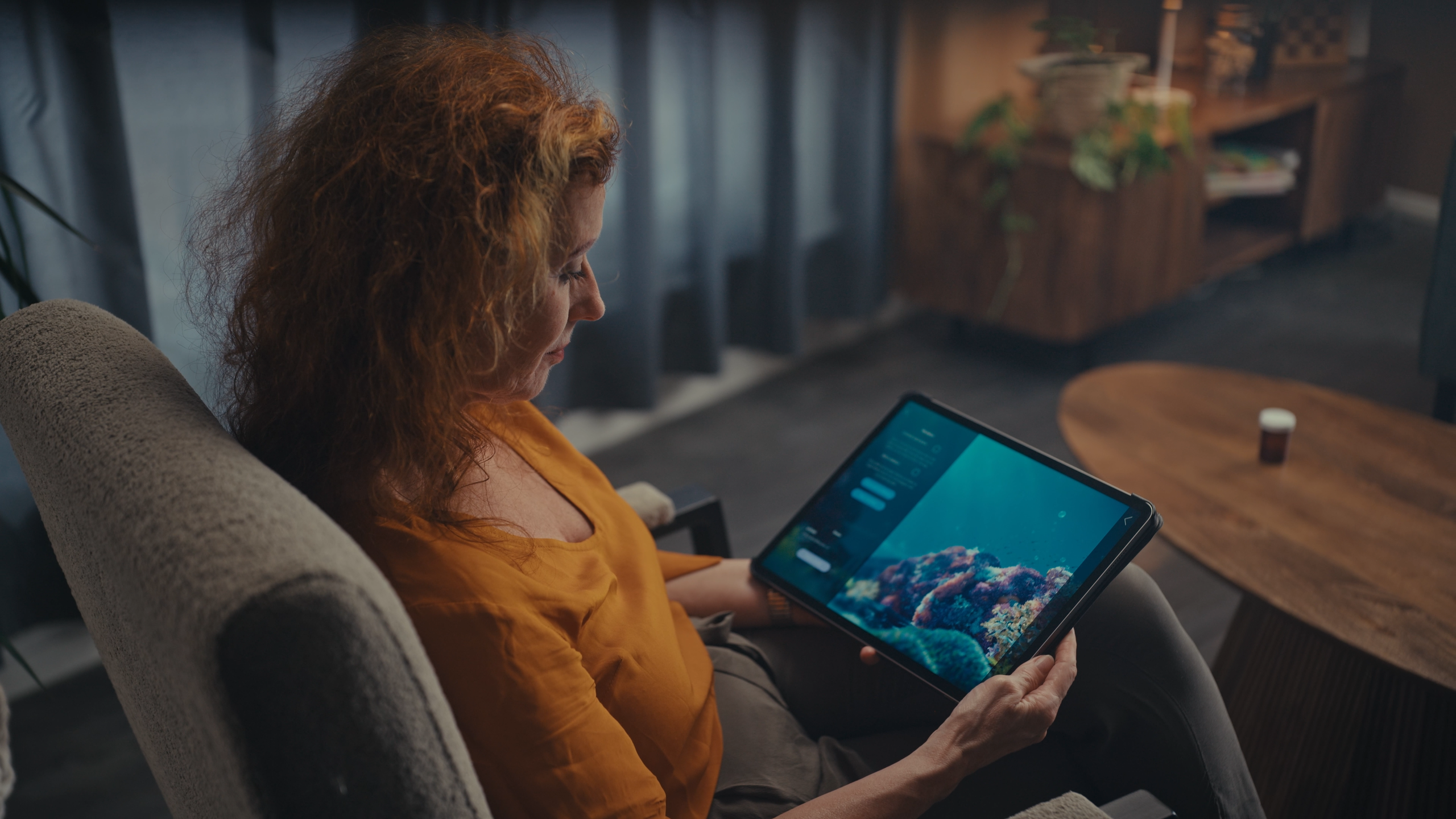 A female caregiver with a tablet in her lap, sitting opposite a patient (taken from Sensu.health's commercial video for VRelax)